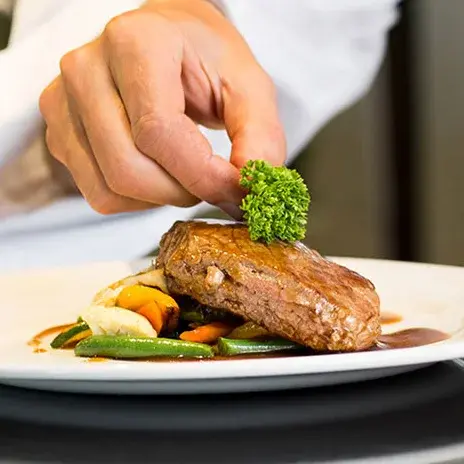 Marlton Gardens Chef Created Meals, chef garnishing a plate.